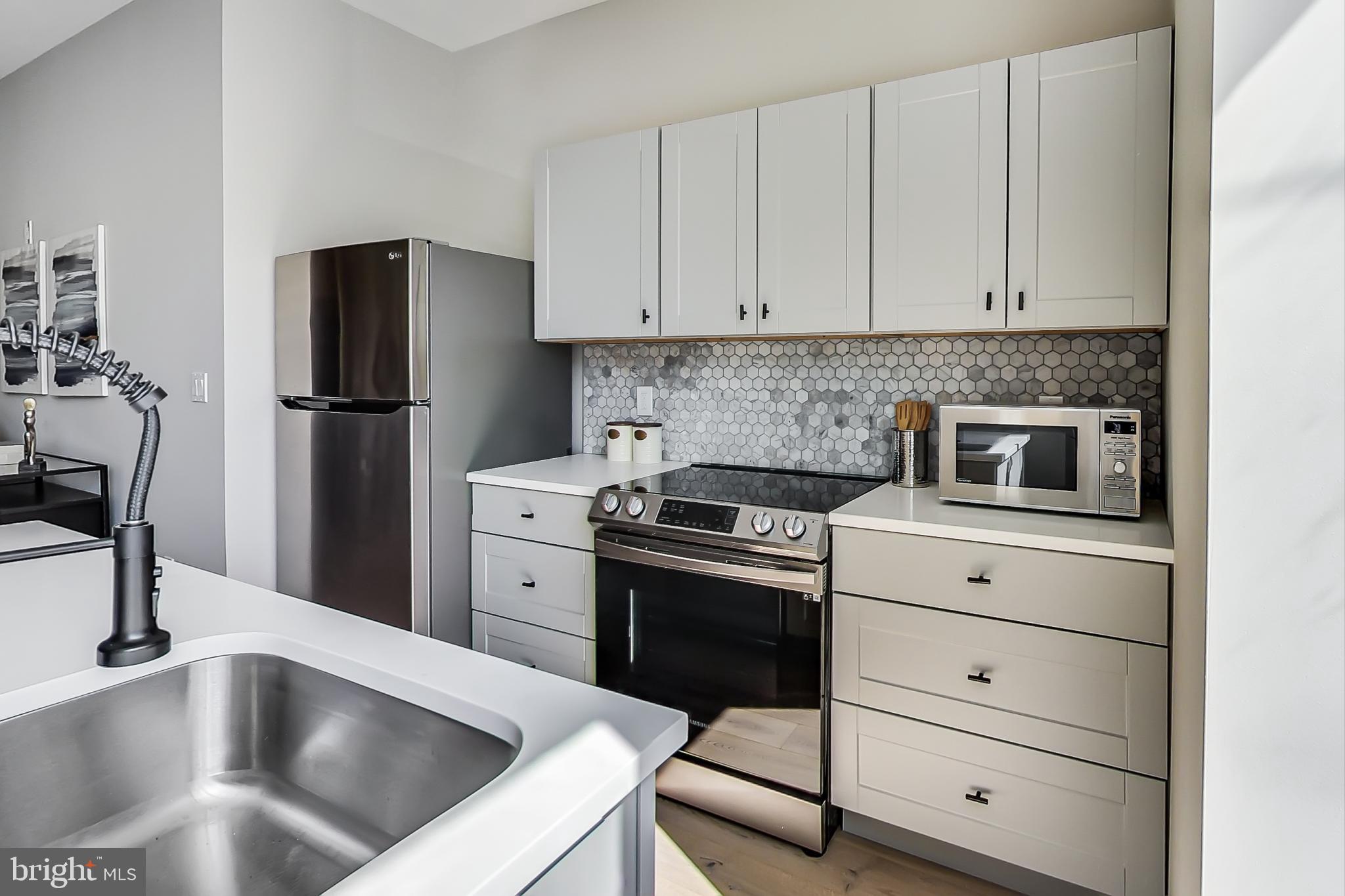 207 Florida Avenue Northwest, Unit 1 Washington, DC 20001 - Photo 7 of 26 a kitchen with white cabinets and stainless steel appliances
