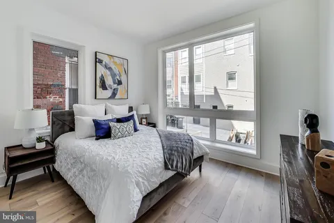 a bedroom with a bed a table and three windows