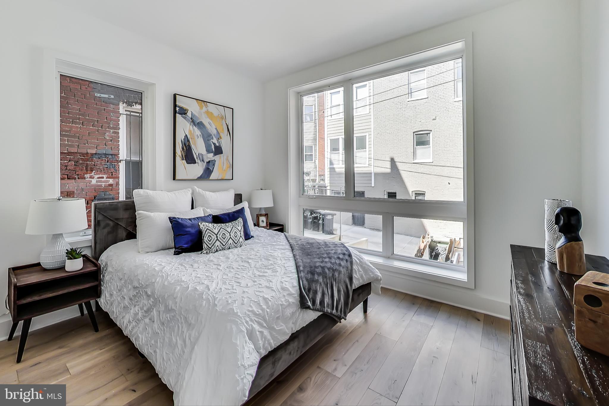 207 Florida Avenue Northwest, Unit 1 Washington, DC 20001 - Photo 10 of 26 a bedroom with a bed a table and three windows