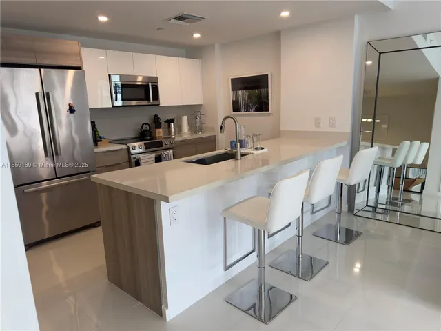 a kitchen with kitchen island a refrigerator stove microwave and sink