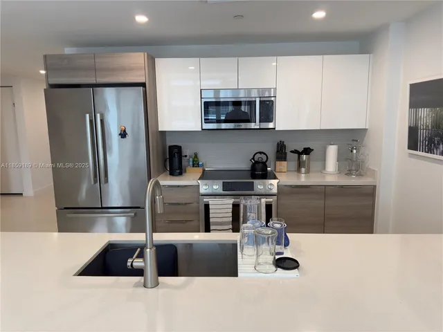 a kitchen with stainless steel appliances granite countertop a refrigerator a stove a sink and a stove