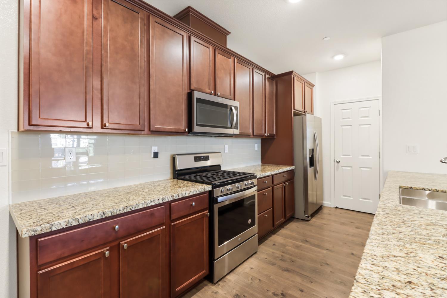 3230 Chelmer Way Rancho Cordova, CA 95670 - Photo 13 of 50 a kitchen with stainless steel appliances granite countertop wooden cabinets a stove top oven a sink and dishwasher