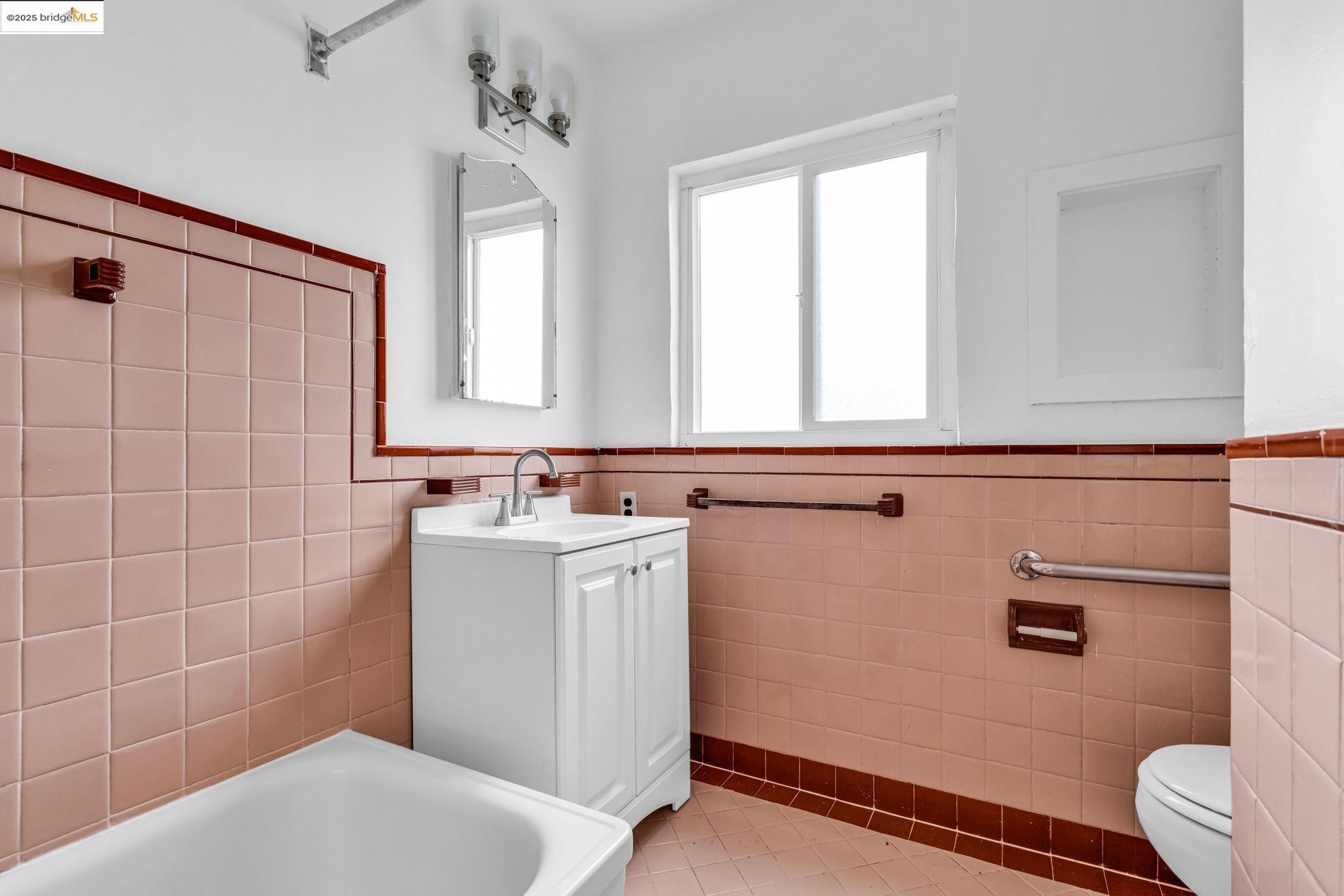 5492 Ruth Avenue Oakland, CA 94601 - Photo 15 of 16 Bathroom featuring a tub to relax in, vanity, wainscoting, light tile patterned floors, and tile walls