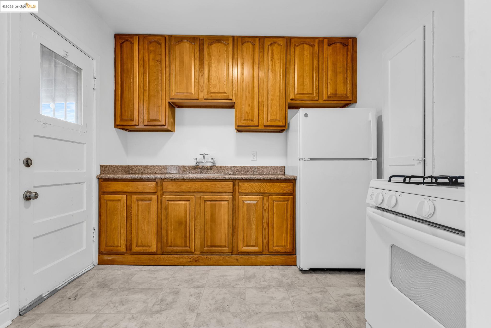 5492 Ruth Avenue Oakland, CA 94601 - Photo 3 of 16 Kitchen featuring white appliances and brown cabinets