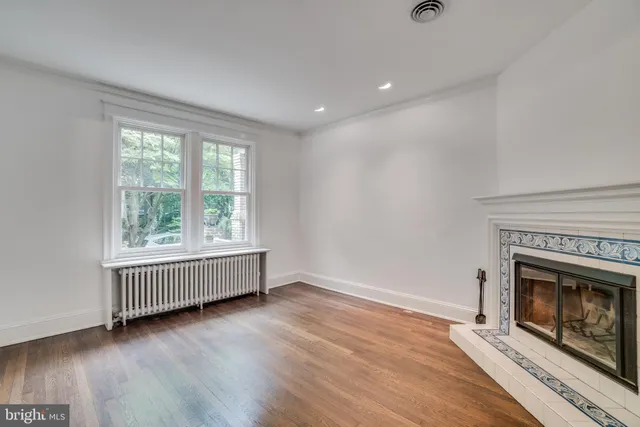 an empty room with wooden floor fireplace and windows