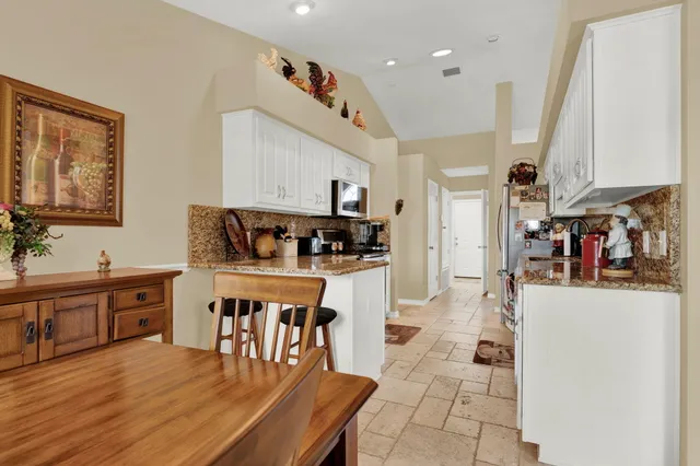 a kitchen with stainless steel appliances granite countertop a refrigerator and white cabinets