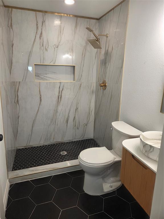 2108 Blake Avenue Dallas, TX 75228 - Photo 8 of 13 Shower with large format marble-look wall tiling, a gold-toned shower system, and an integrated shower niche