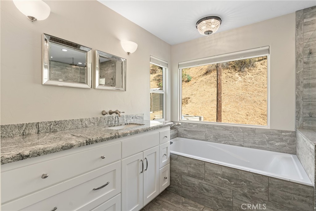 30300 Live Oak Canyon Road Redlands, CA 92373 - Photo 32 of 67 a bathroom with a granite countertop sink a large mirror a bathtub and window