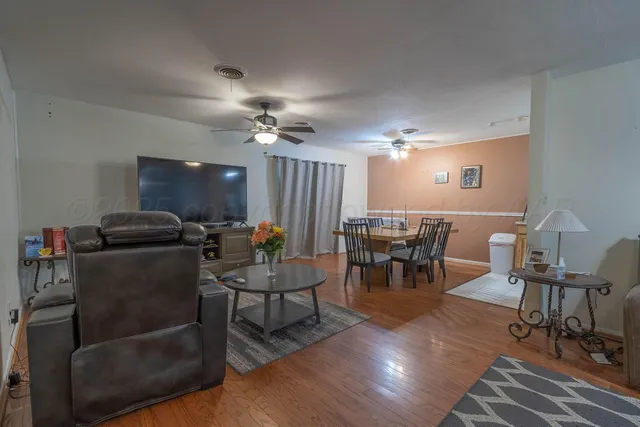 a living room with furniture and a dining table with chandelier