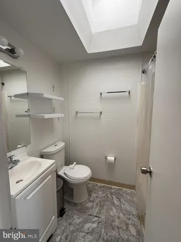 a bathroom with a granite countertop toilet and a sink