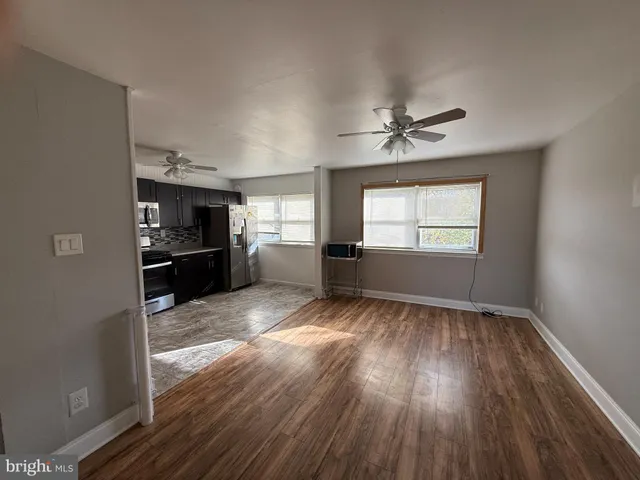 a view of empty room with a kitchen and wooden floor