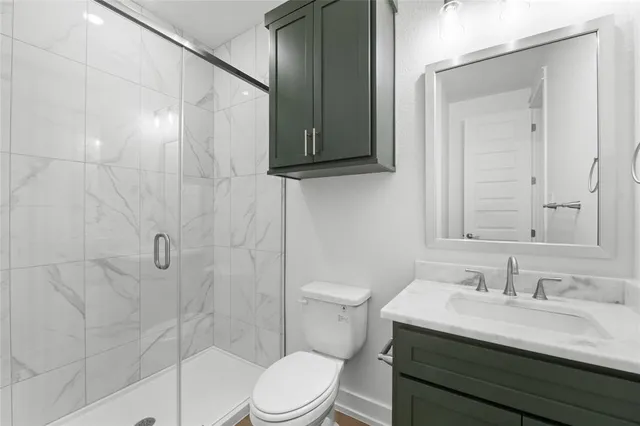 a bathroom with a granite countertop sink a toilet and shower