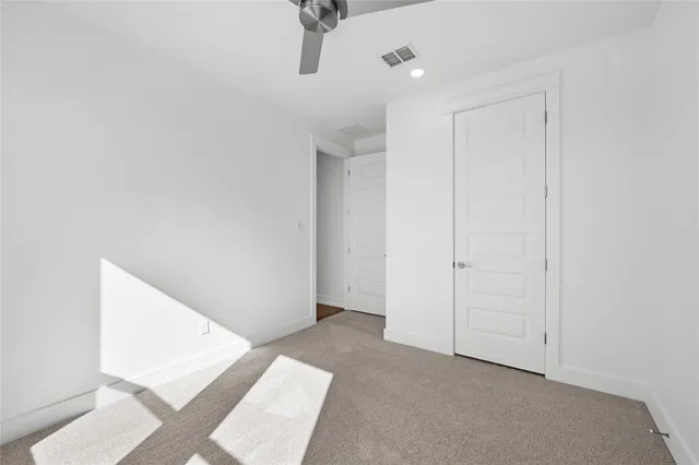 an empty room with a ceiling fan and carpet
