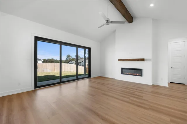 a view of an empty room with wooden floor and a fireplace