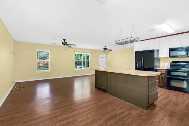 a living room with stainless steel appliances kitchen island wooden floors and living room view