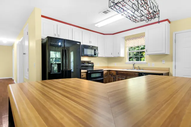 a large kitchen with stainless steel appliances a large counter top a sink a refrigerator and a window