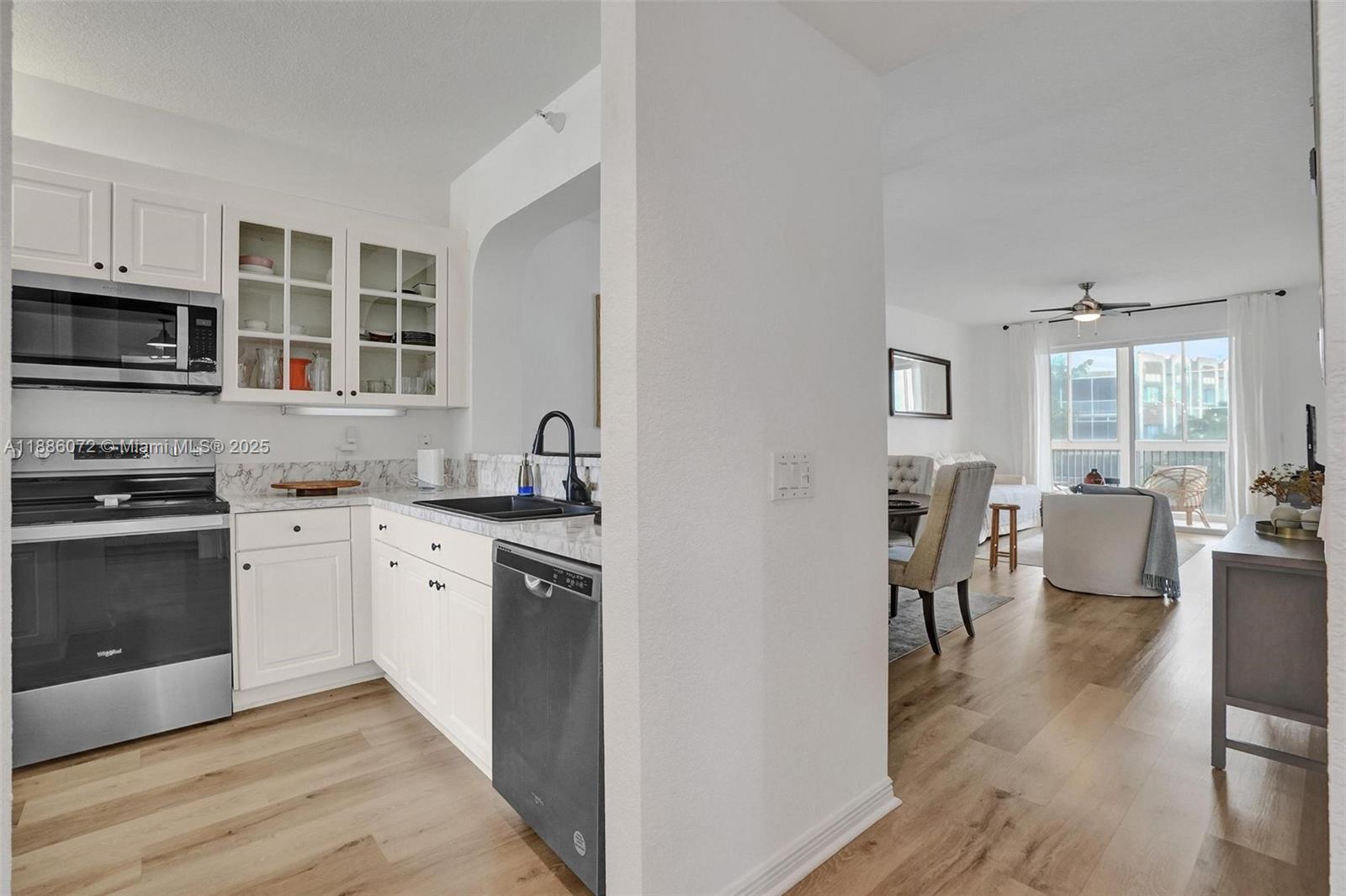 7635 Southampton Terrace, Unit 307 Tamarac, FL 33321 - Photo 15 of 43 a kitchen with stainless steel appliances granite countertop a stove top oven a sink dishwasher a dining table and chairs with wooden floor