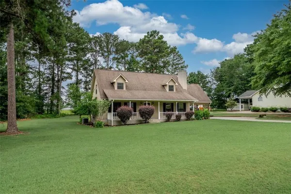 a view of a house with a big yard and large trees