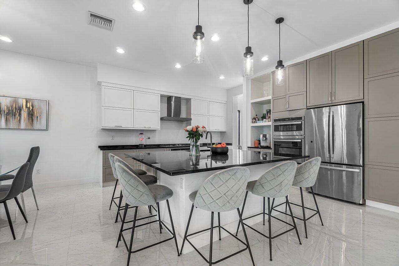 17092 Teton River Road Boca Raton, FL 33496 - Photo 2 of 58 a kitchen with stainless steel appliances kitchen island granite countertop a refrigerator a stove a microwave oven a sink with a dining table and chairs