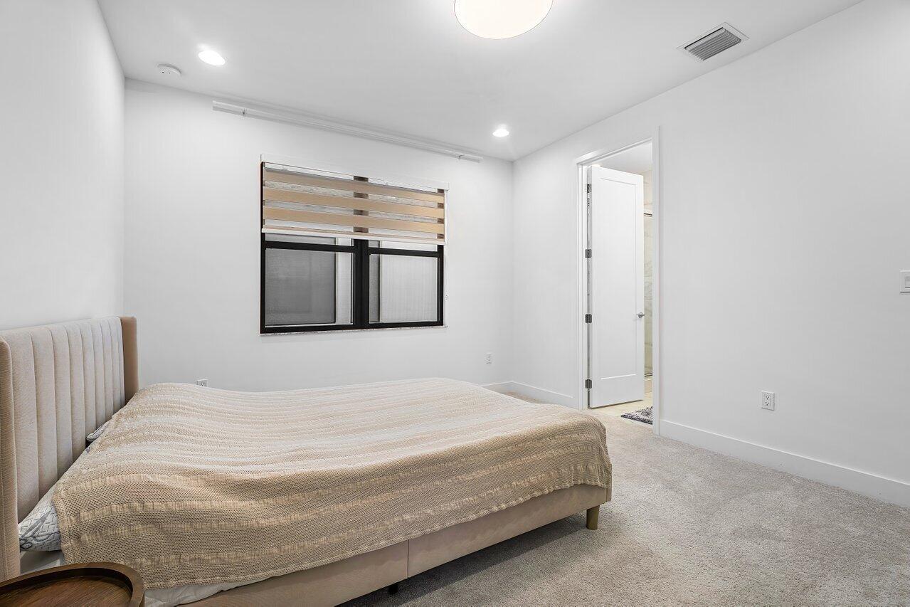 17092 Teton River Road Boca Raton, FL 33496 - Photo 26 of 58 a bedroom with a large bed and a chandelier