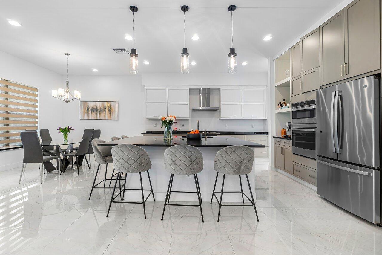 17092 Teton River Road Boca Raton, FL 33496 - Photo 3 of 58 a kitchen with stainless steel appliances kitchen island granite countertop a stove a refrigerator a oven a sink with a dining table and chairs