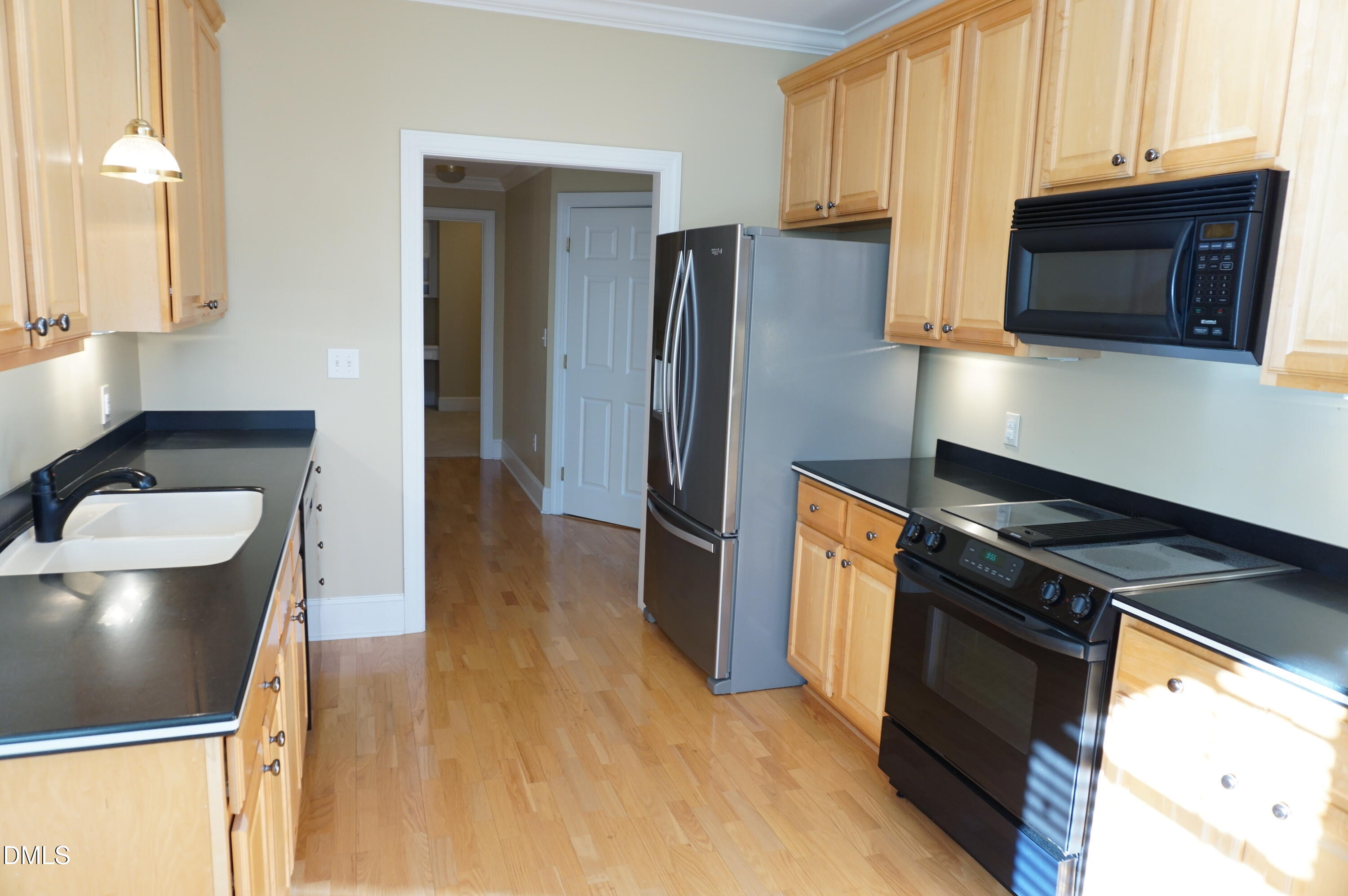 3701 Baron Cooper Pass, Unit 104 Raleigh, NC 27612 - Photo 26 of 52 a kitchen with stainless steel appliances granite countertop a refrigerator a stove and a sink with wooden floor