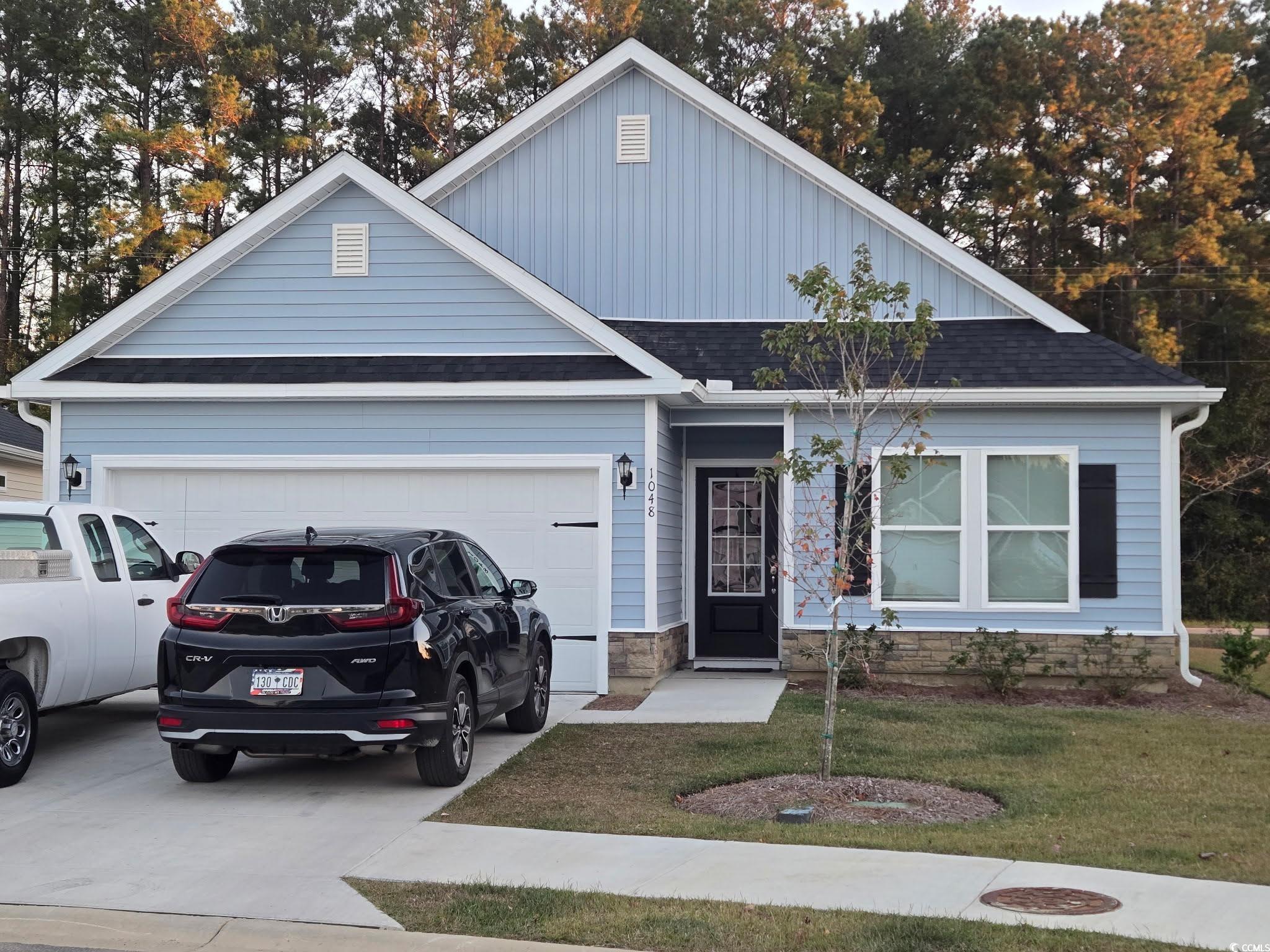 Single story home featuring a front yard, driveway, a garage, and a shingled roof