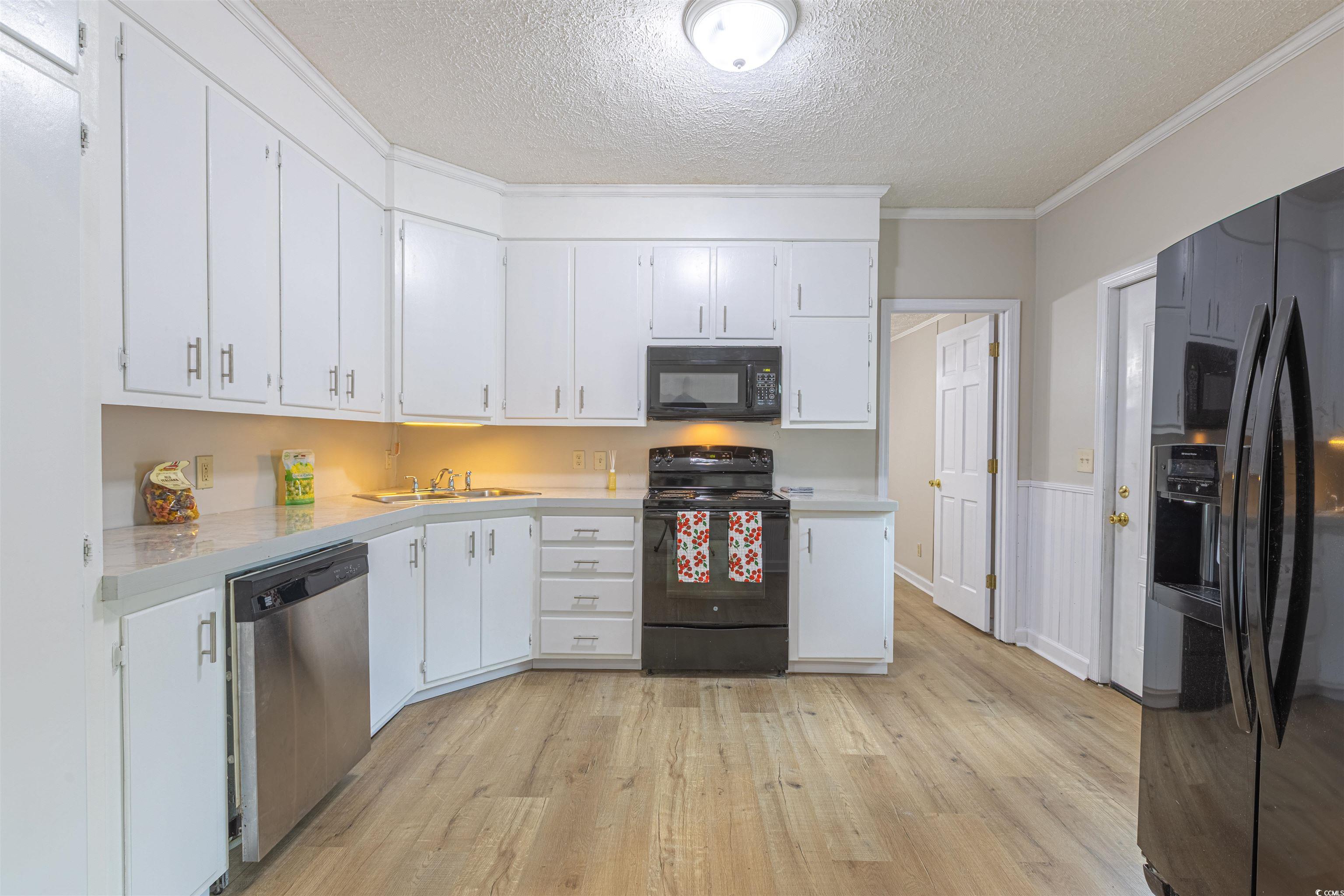 517 Porter Drive Murrells Inlet, SC 29576 - Photo 17 of 40 Kitchen featuring a textured ceiling, black appliances, light countertops, light wood-style flooring, and white cabinets