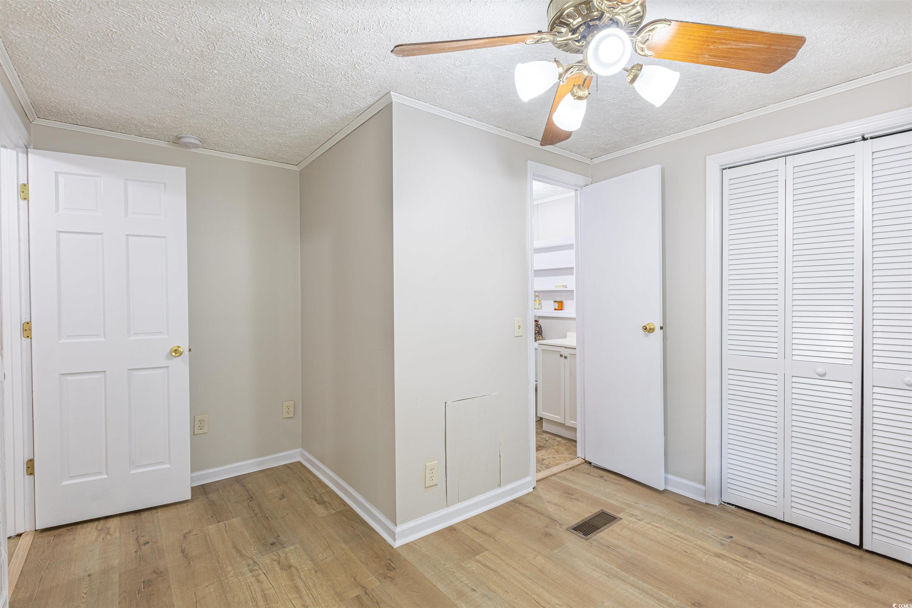 517 Porter Drive Murrells Inlet, SC 29576 - Photo 28 of 40 Unfurnished bedroom with light wood-style floors, a textured ceiling, ornamental molding, a closet, and a ceiling fan