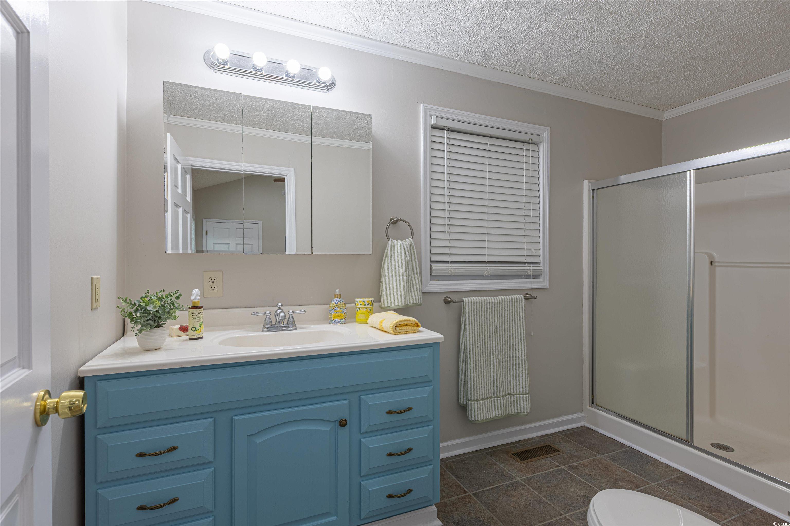 517 Porter Drive Murrells Inlet, SC 29576 - Photo 36 of 40 Full bathroom with ornamental molding, vanity, a shower stall, a textured ceiling, and tile patterned flooring