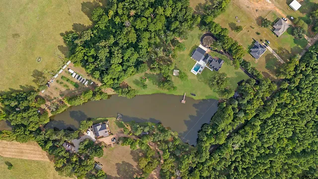 an aerial view of residential house with outdoor space and trees all around