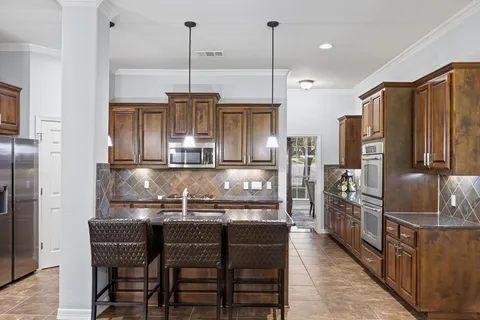 a kitchen with stainless steel appliances granite countertop a kitchen island a stove and a refrigerator