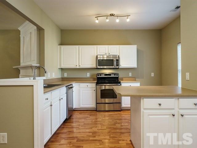 4213 Vienna Crest Drive Raleigh, NC 27613 - Photo 11 of 24 a kitchen with stainless steel appliances kitchen island granite countertop a sink and cabinets