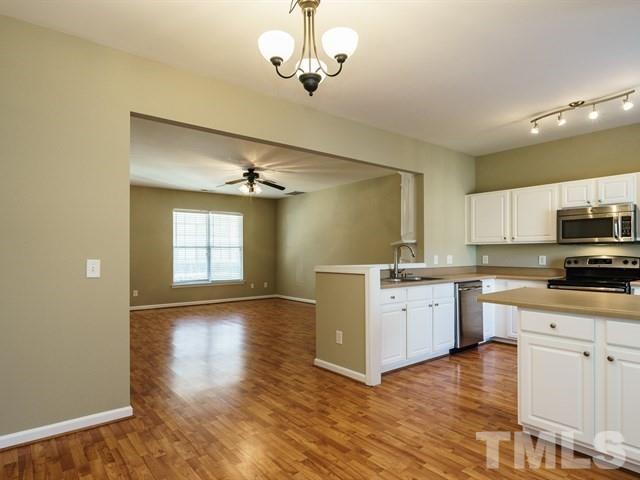 4213 Vienna Crest Drive Raleigh, NC 27613 - Photo 10 of 24 a kitchen with a white cabinets and chandelier