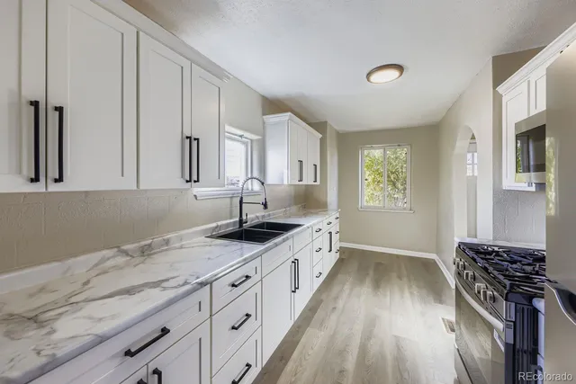 a kitchen with granite countertop a sink stove and cabinets