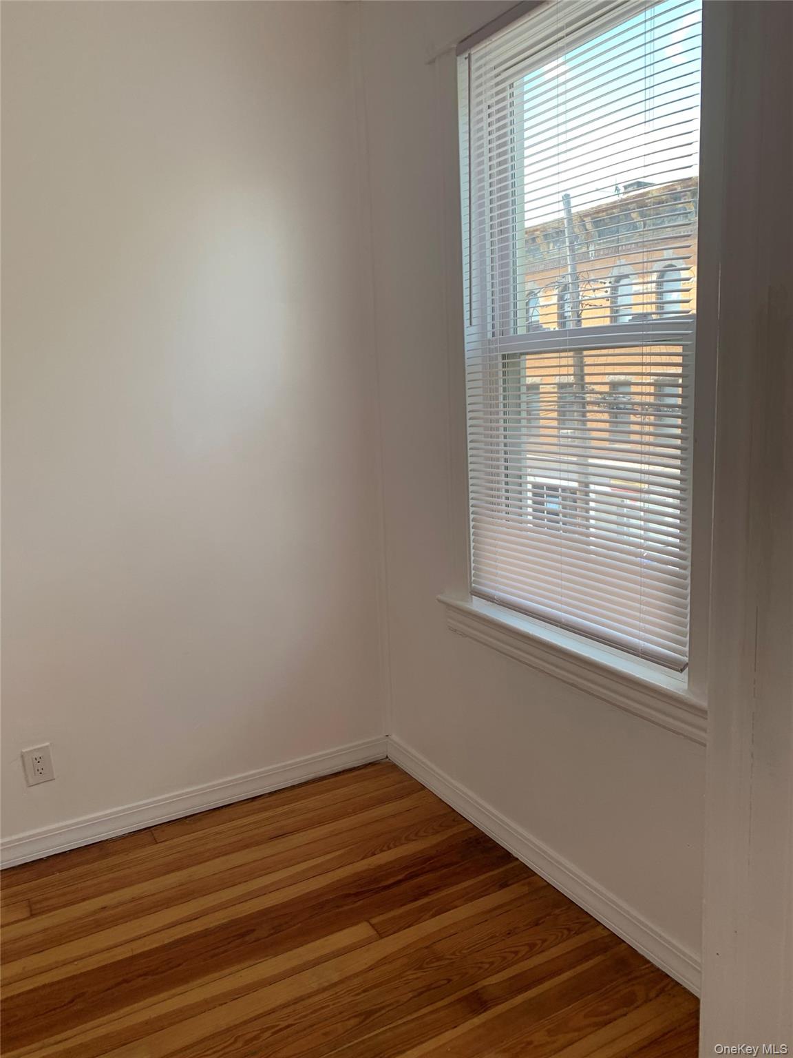 60-24 56th Road, Unit 2 Queens, NY 11378 - Photo 12 of 14 an empty room with wooden floor and windows