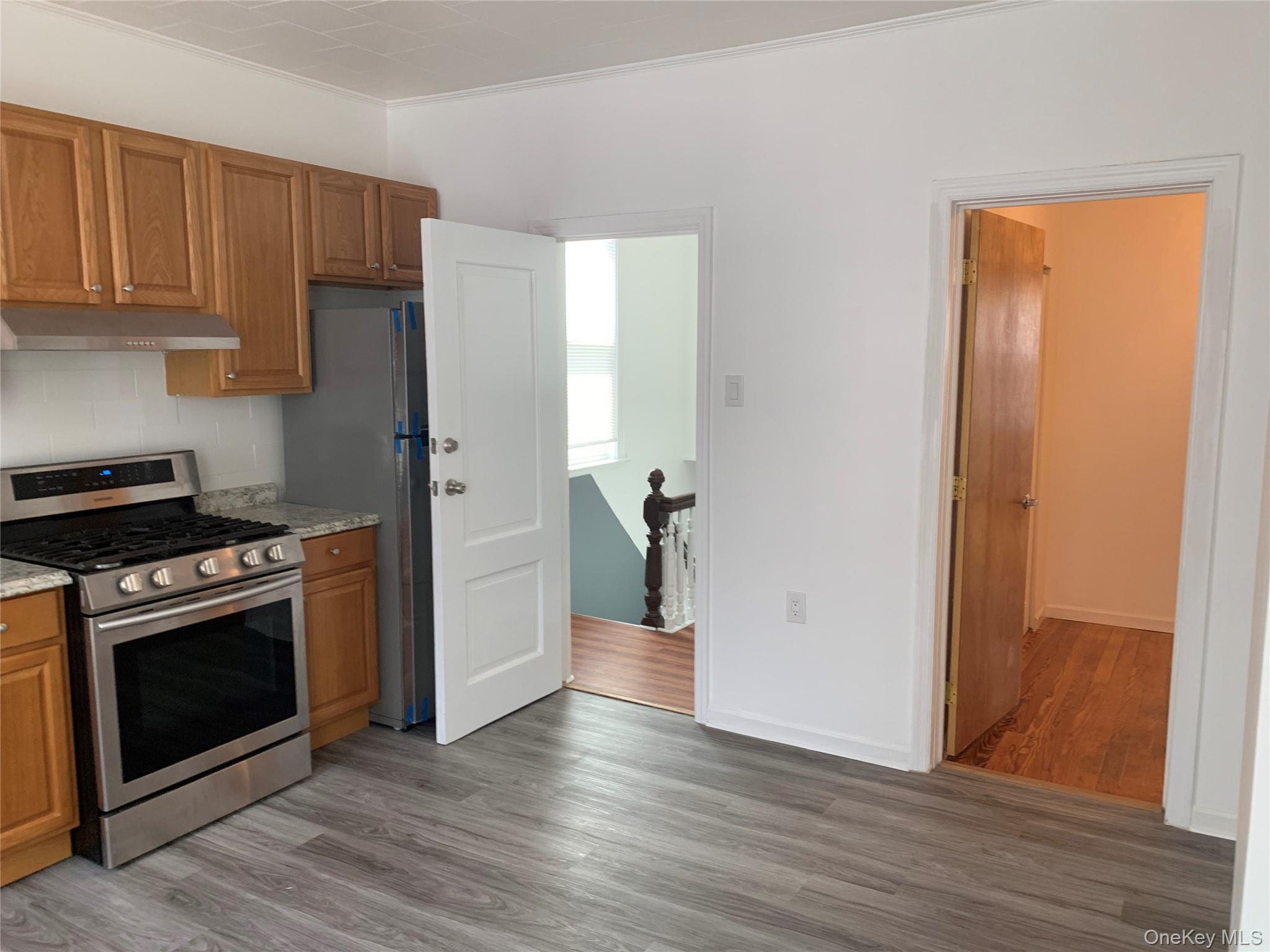 60-24 56th Road, Unit 2 Queens, NY 11378 - Photo 4 of 14 a kitchen with wooden floor and a stove top oven
