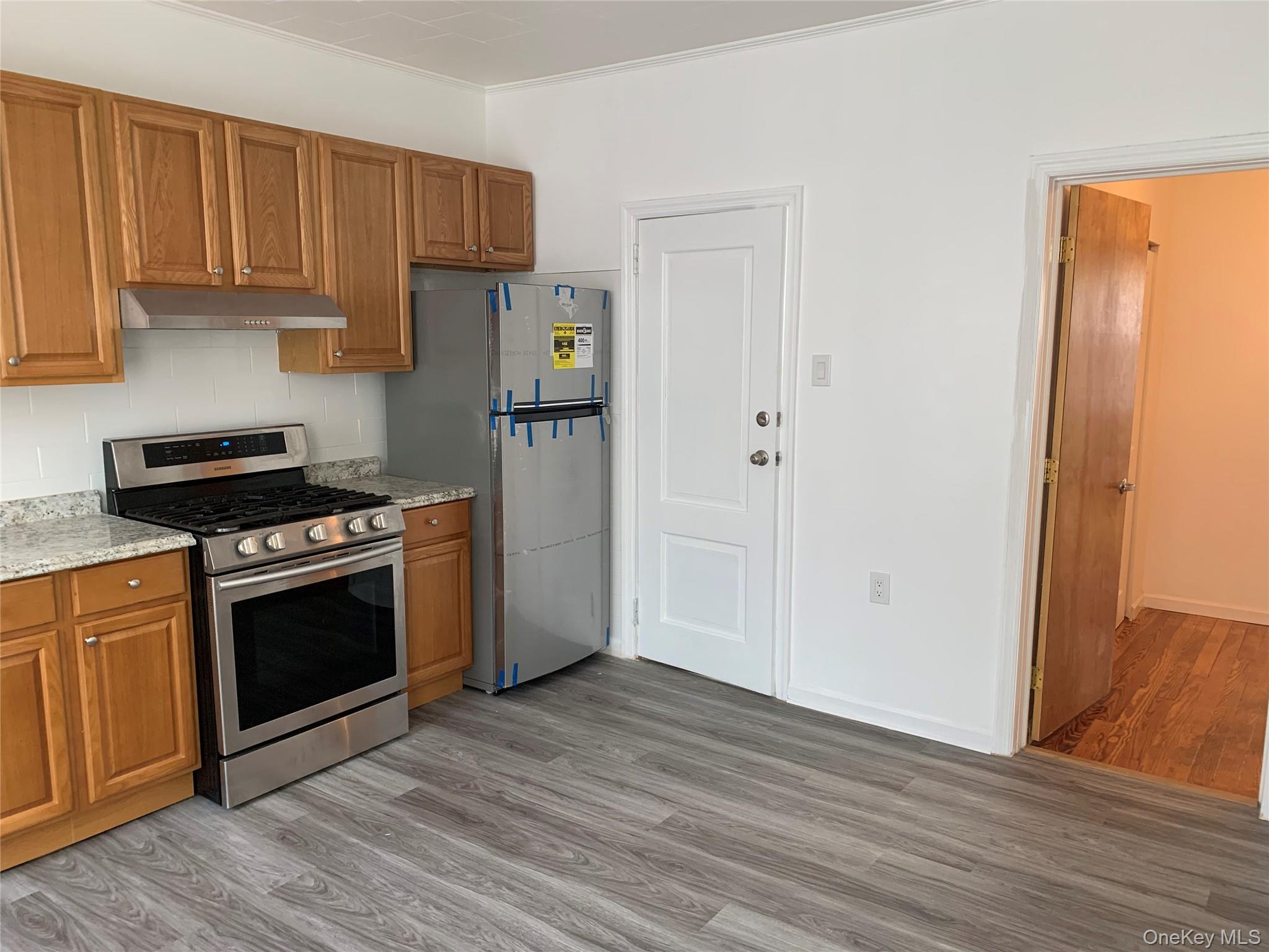 60-24 56th Road, Unit 2 Queens, NY 11378 - Photo 5 of 14 a kitchen with granite countertop a stove and a refrigerator