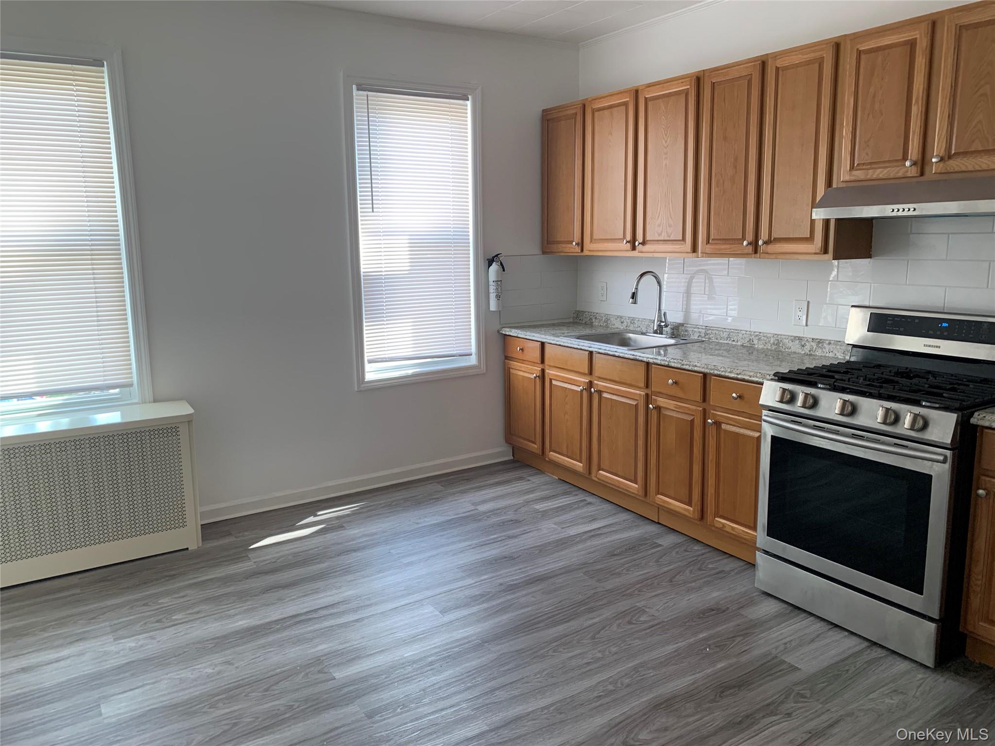 60-24 56th Road, Unit 2 Queens, NY 11378 - Photo 7 of 14 a kitchen with granite countertop wooden floors and stainless steel appliances