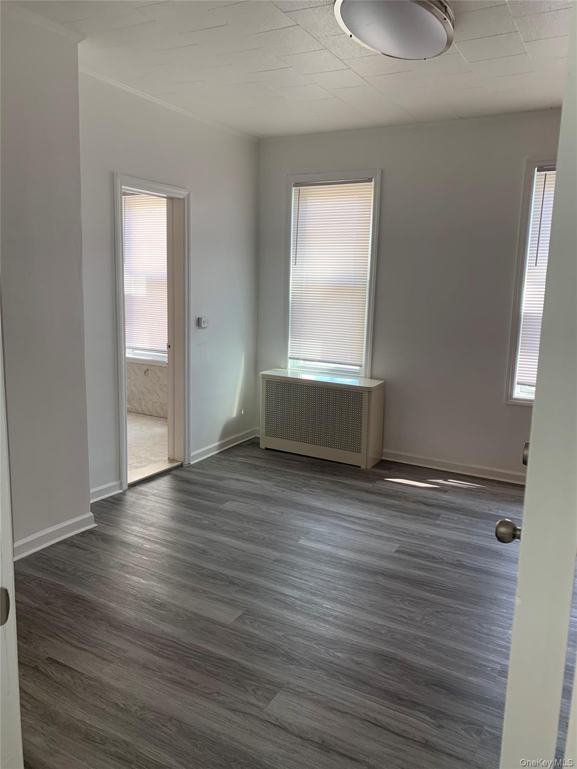 60-24 56th Road, Unit 2 Queens, NY 11378 - Photo 8 of 14 an empty room with wooden floor and windows