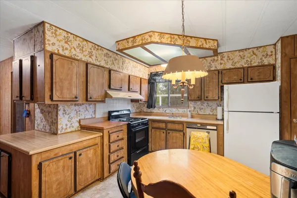 a kitchen with stainless steel appliances granite countertop a sink a stove a refrigerator a washer and dryer