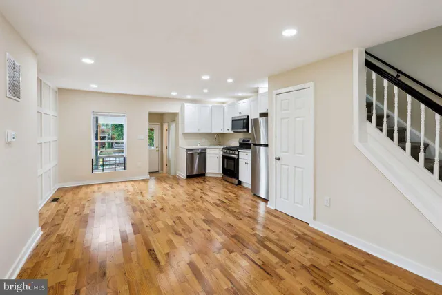 a view of an empty room with kitchen and a window