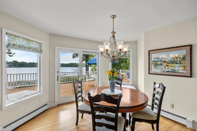 a kitchen with stainless steel appliances granite countertop a refrigerator a stove top oven a dining table and chairs with wooden floor