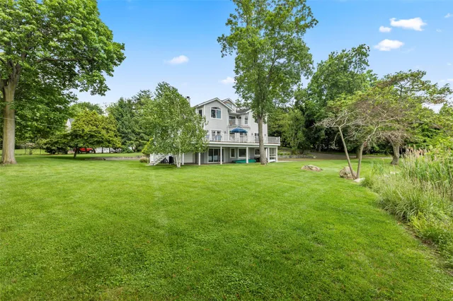 a view of a house with a big yard and large trees
