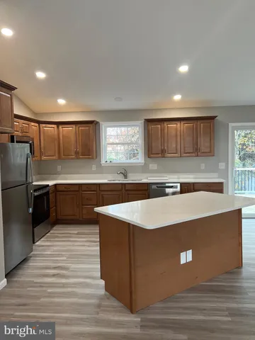 a large kitchen with stainless steel appliances granite countertop a large counter top a sink and a refrigerator