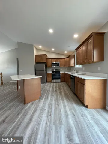 a large kitchen with stainless steel appliances kitchen island a large counter top and a stove top oven