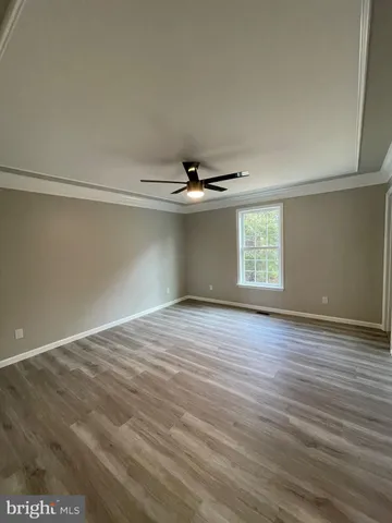 an empty room with wooden floor chandelier and windows