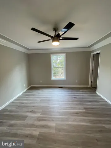 an empty room with wooden floor ceiling fan and windows