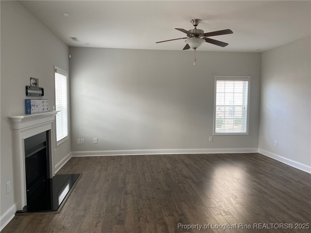 277 Pendleton Street Raeford, NC 28376 - Photo 2 of 29 an empty room with wooden floor fireplace and windows