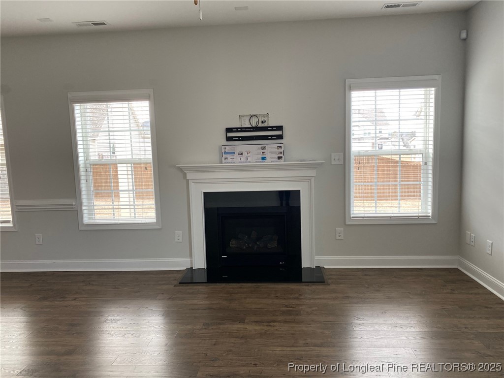 277 Pendleton Street Raeford, NC 28376 - Photo 5 of 29 an empty room with wooden floor a fireplace and windows